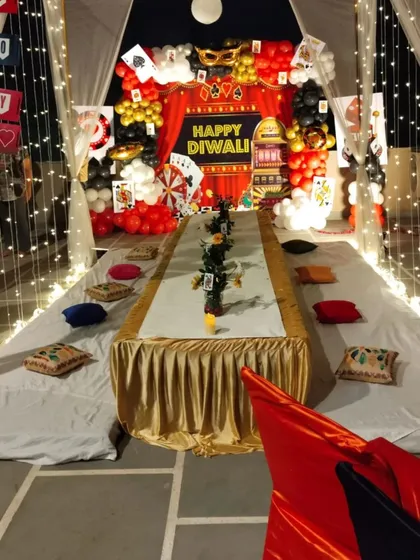 A cozy and fun casino-themed Diwali party setup on a terrace, with a canopy of fairy lights and low seating.