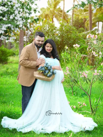 A romantic couple's portrait in a garden, with the mother-to-be in a light blue gown.