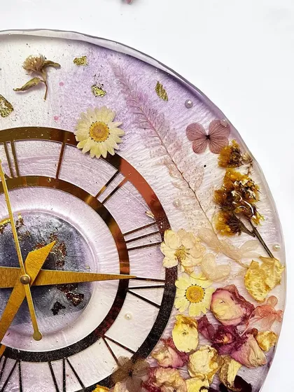 A close-up of a beautiful 12-inch clock with a lavender-themed design. The preserved flowers and gold details look so elegant against the purple resin.