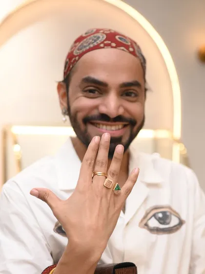 A guest joyfully shows off a hand full of statement rings he is trying on. Styling should be fun and expressive.