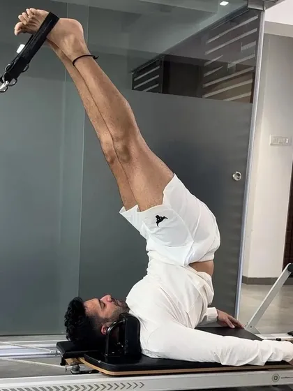 A male client performs a leg series on the Reformer, demonstrating that Pilates is highly effective for men looking to build core strength, improve flexibility, and enhance overall fitness.