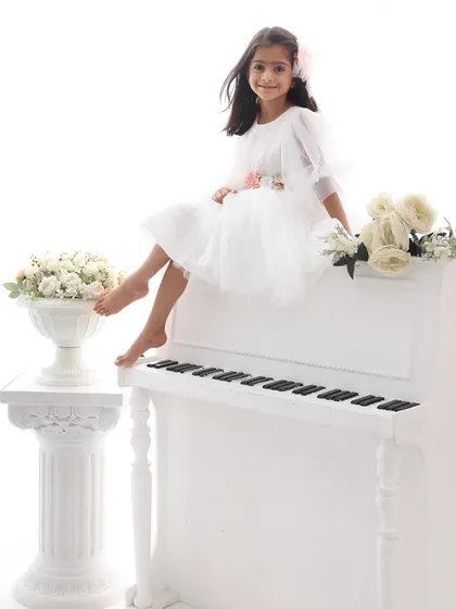 Poised and graceful. Sitting atop the white piano, this young lady looks like a true artist. This theme is wonderful for capturing the elegance and growing personality of older children.