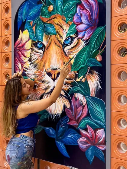 In the process of painting the tiger's face, focusing on the intense blue eyes that are the focal point of the piece.