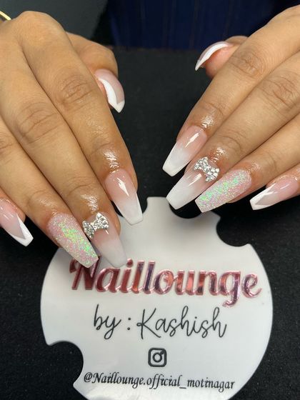 A classic white ombre on coffin nails, elevated with glitter accent nails and 3D rhinestone bows.