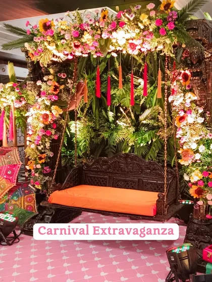 A "Carnival Extravaganza" Mehendi theme, featuring a beautifully carved wooden swing (jhoola) decorated with a riot of colorful flowers.