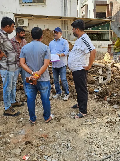 In discussion with the project team at a demolition site, planning the Vastu for the new structure that will be built here.
