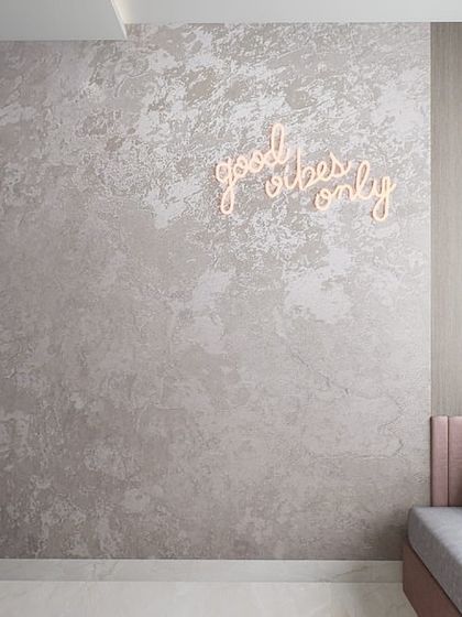 This modern minimalist room features a cozy daybed with a neon sign, creating a cool and personalized hangout spot for a young adult.