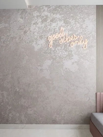 This modern minimalist room features a cozy daybed with a neon sign, creating a cool and personalized hangout spot for a young adult.
