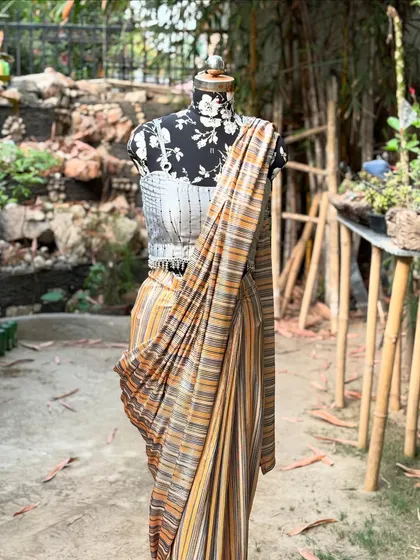 The combination of the modern blouse and the traditionally inspired striped saree creates a unique fusion look.