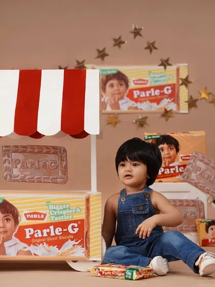 The full setup of the nostalgic Parle-G themed birthday shoot, with the baby girl sitting by a custom-made biscuit stall.