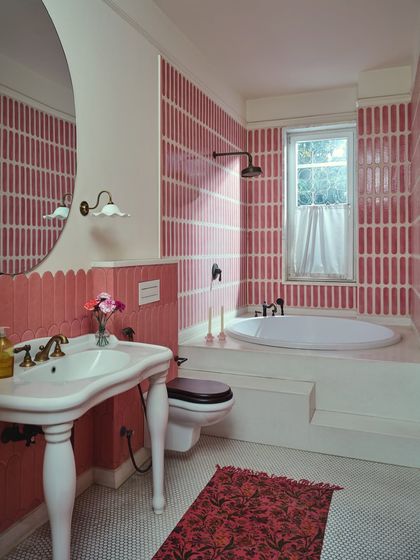 The mulberry-toned bathroom, with its custom-cut pink tiles and vintage-style pedestal sink. The design feels both composed and unabashedly romantic, with ornate brass fittings that feel like they've always been part of the home.