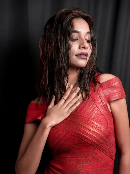 A quiet, sensual moment in the studio. The model in a red dress looks down, her wet hair and the dark background adding to the moody, editorial feel.