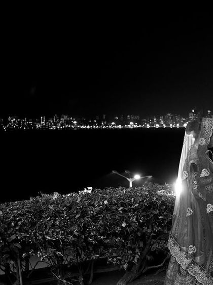 A stunning black and white photograph of a newlywed couple against the backdrop of the Mumbai skyline at night. This image combines the intimacy of the couple with the grandeur of the city.