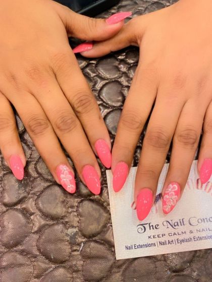 A soft and pretty set of pink stiletto nails. The ring fingers are accented with a delicate, hand-painted white floral design.