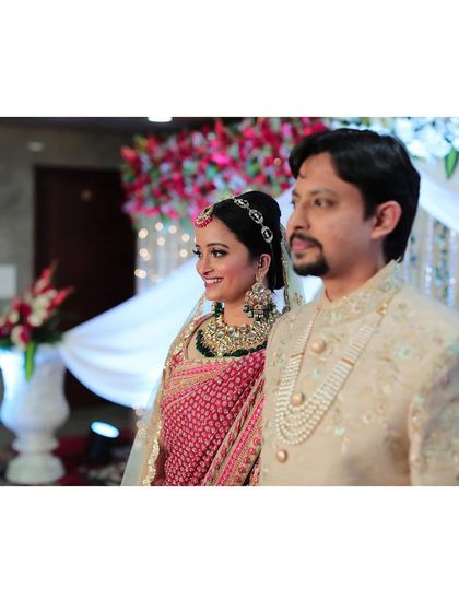 The happy couple, ready for their reception. The bride's makeup is coordinated with her red lehenga, creating a cohesive and stunning look.
