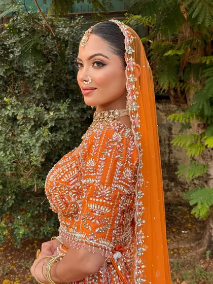 Every feature enhanced, every detail perfected. This bride in a vibrant orange lehenga is the perfect balance of soft glam and timeless elegance.