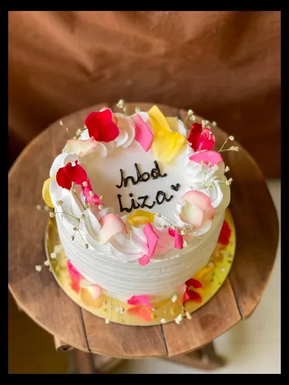 A side view of the floral birthday cake, showing the delicate arrangement of rose petals.