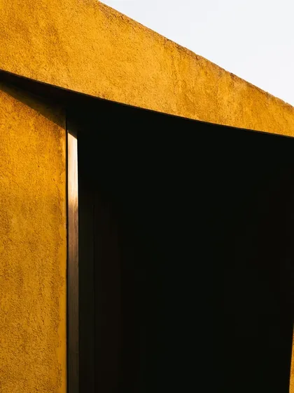 An abstract detail of the architecture, where a sharp incision in the wall creates a dramatic, dark doorway.