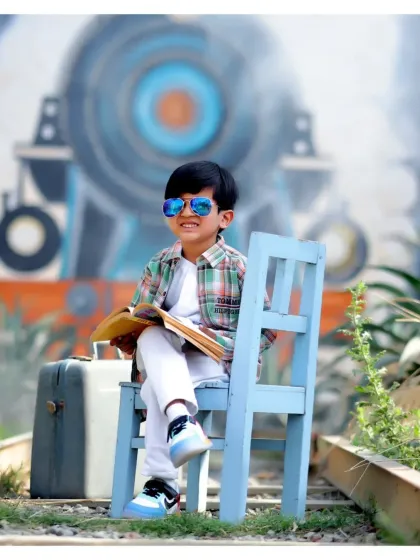 A cool and confident pose from a young boy during his outdoor train-themed shoot. The natural light and dynamic background create a powerful image.