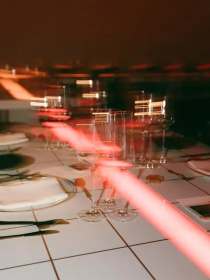 An atmospheric, motion-blur shot of the table setting at Rohan's 30th. The red lights and glassware capture the vibrant, glowing energy of a really good night.