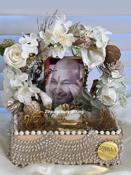 A sophisticated Guruji Darbar featuring a serene white and gold color palette. The arrangement is built on a decorative box base with intricate pearl detailing, perfect for a special occasion.