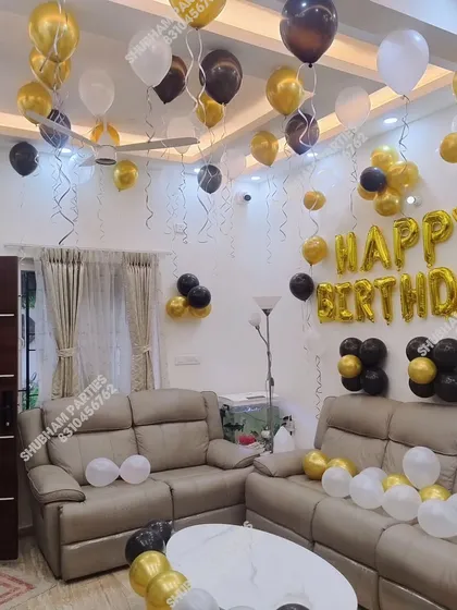 An elegant living room setup with black, gold, and white balloons for a sophisticated party.