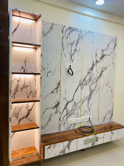 A stunning TV unit with a full-height marble laminate backdrop and gold inlay details. The design includes an illuminated display column and a floating wooden console.