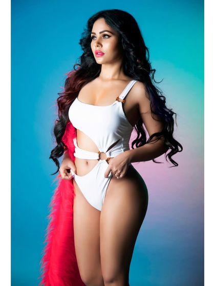 A vibrant studio shot with a colorful background, featuring a white monokini and a bright pink fur accessory. This shows my range with bold, high-energy fashion concepts.
