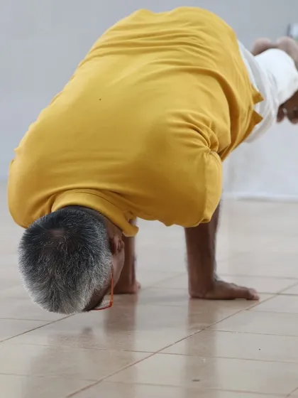 A student demonstrates Mayurasana, the peacock pose, an advanced arm balance that requires significant core strength and balance.
