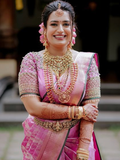 A radiant portrait of the bride in her pink Kanjivaram saree, her smile lighting up the frame. This shot captures her joy and elegance.