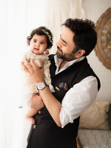 A proud father holds his beautiful baby girl in this heartwarming portrait.