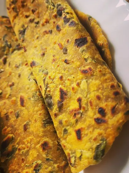 A close-up of the Methi Parathas, showing the specks of green fenugreek leaves and the perfectly cooked, flaky texture.