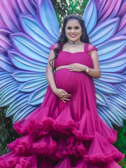 A vibrant solo portrait in front of the popular angel wings set. The mom-to-be's happy smile and the colorful backdrop create an image that is full of life and joy.