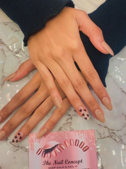 A subtle and sweet design on long, almond-shaped nails. The nude base is accented with a single nail on each hand featuring a tip covered in tiny, hand-painted black hearts.