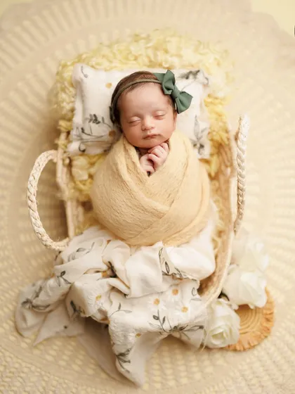 Soft yellows and greens create such a cheerful and sunny vibe. This little girl is nestled in a basket bed with a cute bow, looking like a little ray of sunshine.