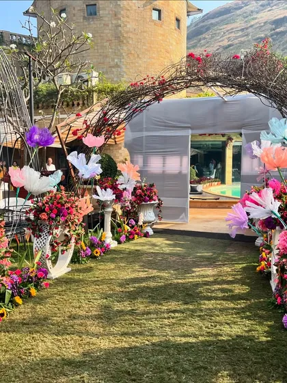 The entrance walkway for the Haldi, decorated with a rustic twig arch and vibrant paper flowers.
