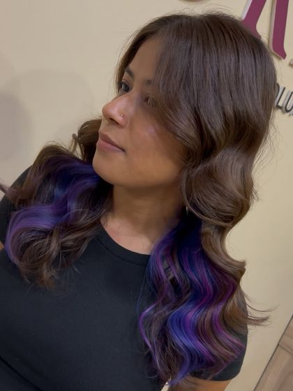A creative hair color placement with peekaboo purple highlights, demonstrating a fun and trendy coloring technique.