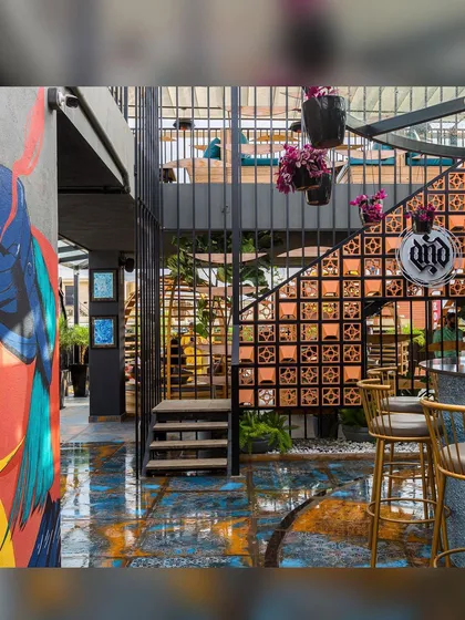 A view of the bar counter transformation, showing the finished space with its custom flooring, terracotta jali wall, and vibrant pop-art mural. The design is a fusion of industrial structure and artistic expression.