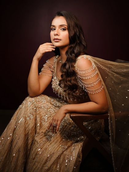 My golden girl, shining bright. This cocktail makeup look features soft, bronzy tones and a flawless finish that complements her sparkling champagne lehenga perfectly.