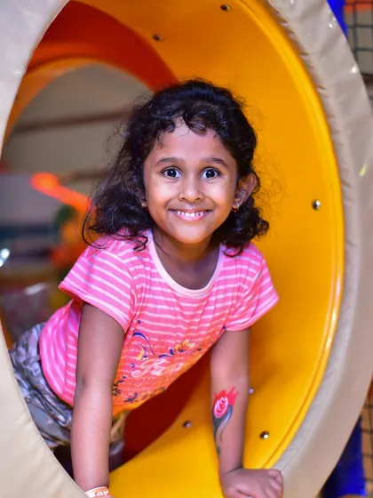 A happy girl crawling through one of our colorful play tunnels. Our structures are designed to encourage exploration and physical activity.