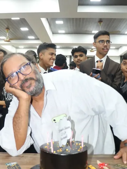 One of our senior teachers posing playfully with the farewell cake, capturing the fun spirit of the evening.