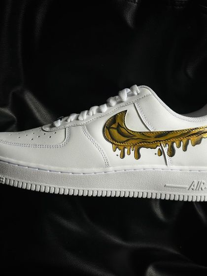 A custom Nike Air Force 1 with a liquid gold dripping swoosh design.