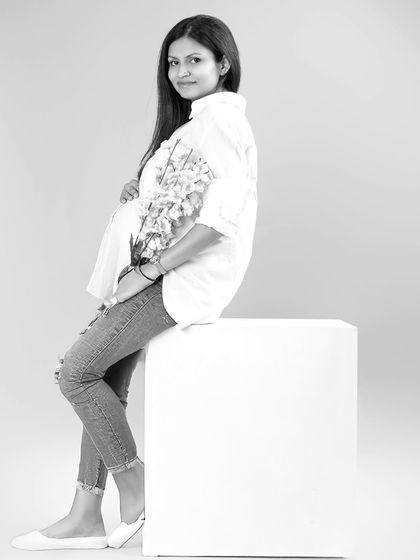 A relaxed and minimalist portrait in black and white. The mother-to-be is styled in a simple white shirt and jeans, creating a timeless and natural look that feels effortlessly beautiful.