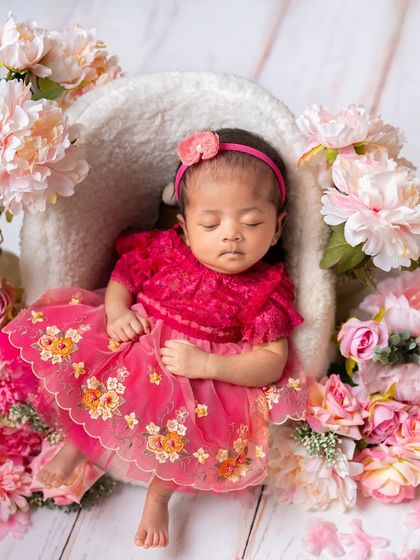 This little princess is resting in her floral throne. The combination of a detailed dress and abundant pink flowers creates a rich and beautiful composition.