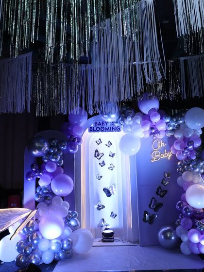 For our 'Baby is Blooming' theme, I created this enchanting butterfly wonderland. The purple and silver balloons, shimmering streamers, and fluttering butterflies made for a magical photo backdrop.