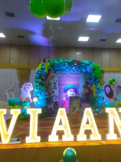 A large-scale jungle theme birthday stage with marquee letters spelling 'VIAANSH' and a custom photo backdrop.