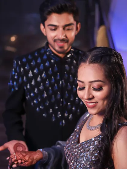 A candid moment showing the bride's henna and her glamorous Sangeet makeup. The look is designed to be beautiful from every angle.