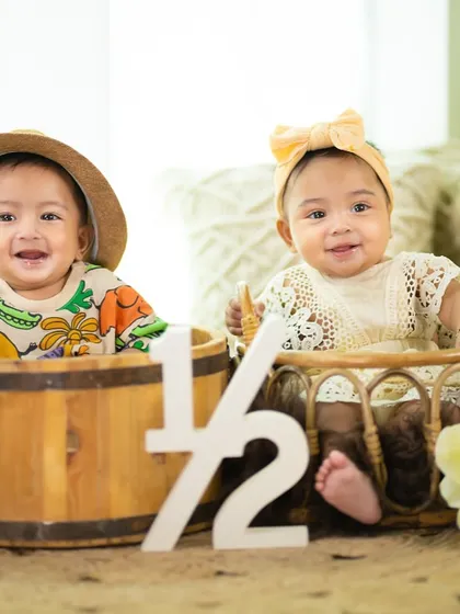Twin babies celebrating their half-birthday. Their matching smiles and coordinated outfits are absolutely precious.