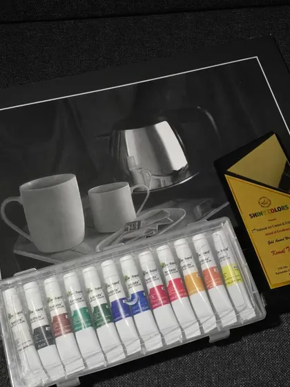 My award-winning artwork alongside the trophy and a set of paints I received as a prize.