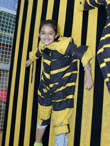 A big smile from a child stuck on the velcro wall. This activity is great for building confidence and having a good laugh.